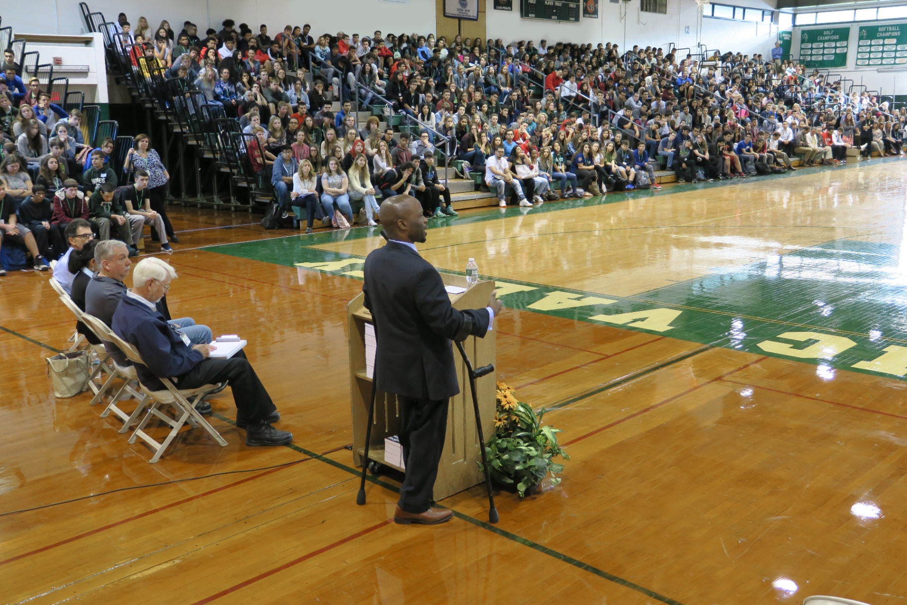 Hashim speaking to a packed high school gymnasium assembly